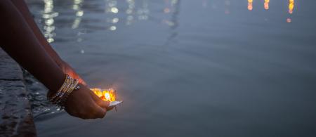 A evening shot of a woman putting blessed puja flowers in the river Ganges in Varanasi, India